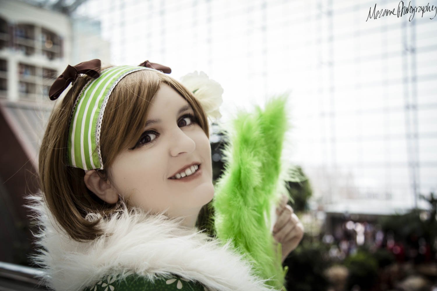 Looking over shoulder, holding green feather fan.