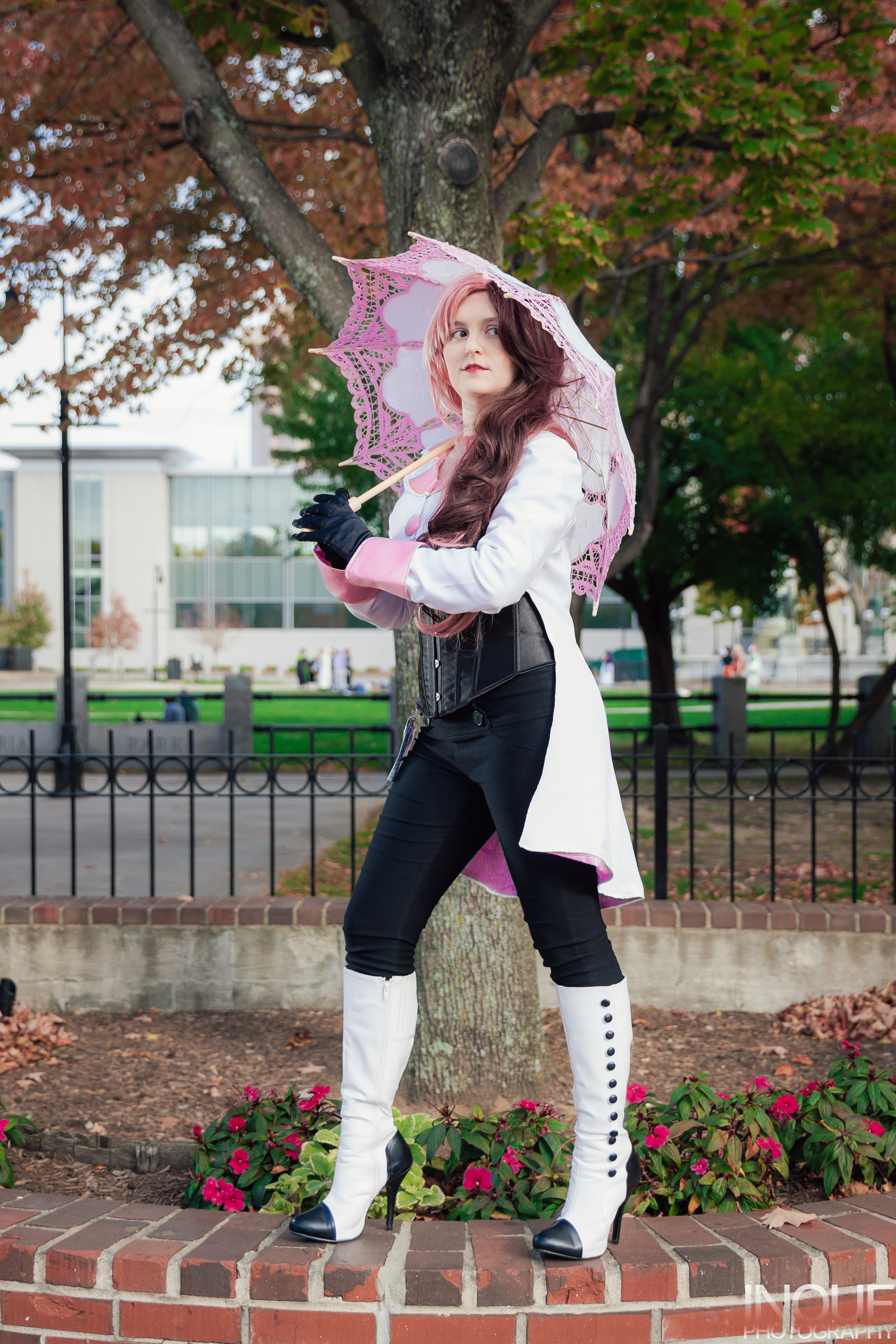 Neo standing with feet apart on a brick wall, holding a parasol.