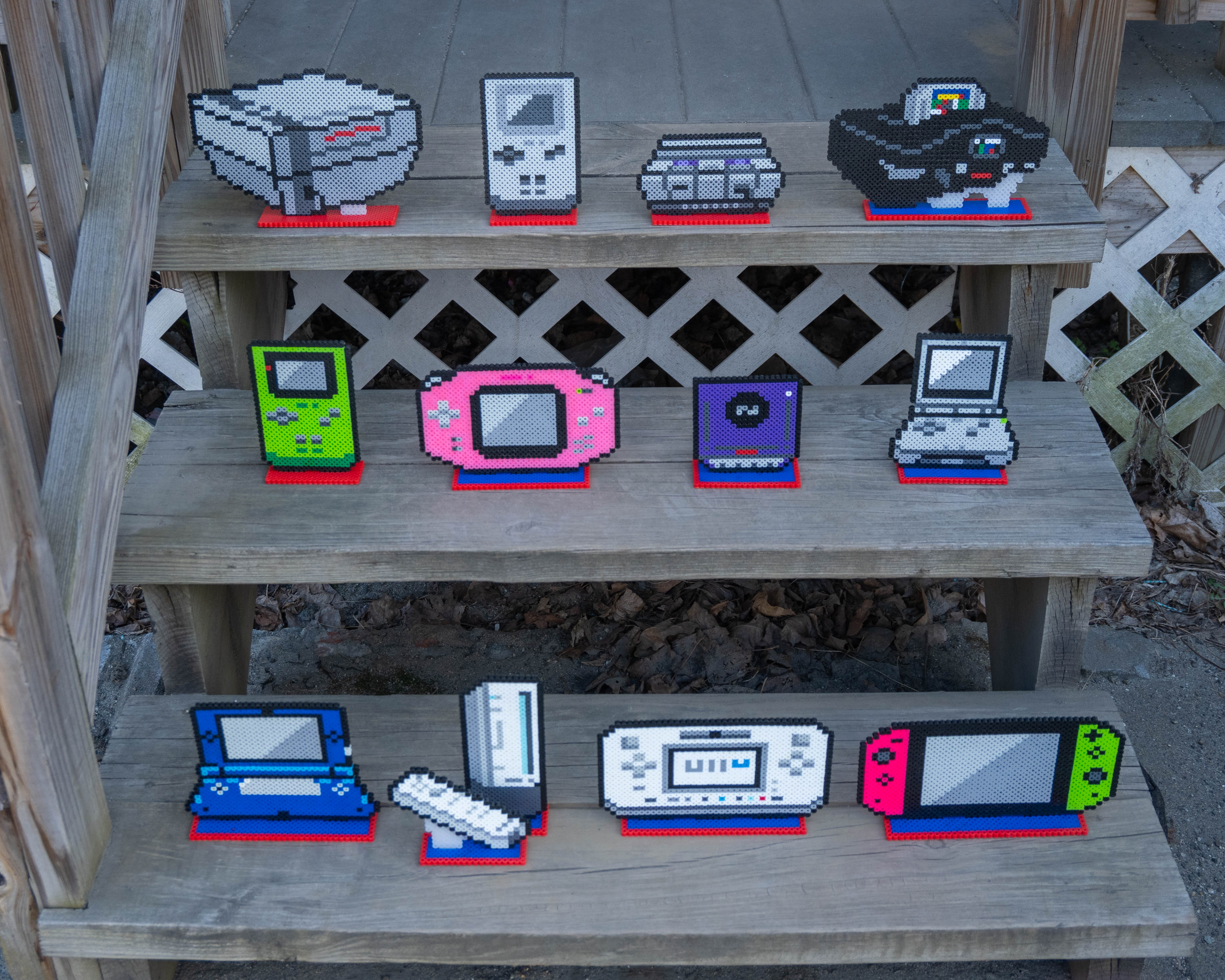 All Nintendo Consoles made out of perler beads, arranged on stairs.