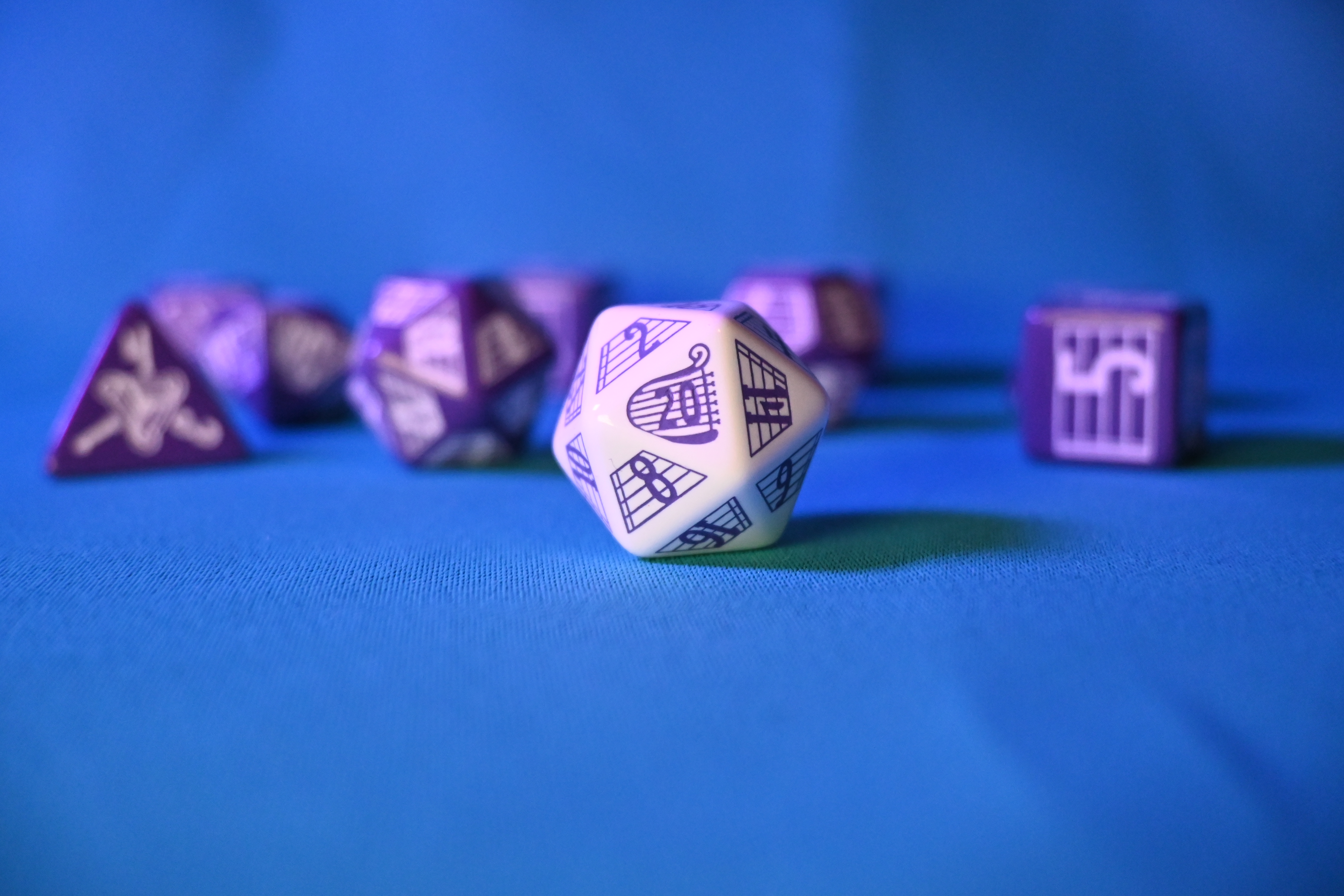 A set of bard-inspired white and purple dice with the D20 in front.