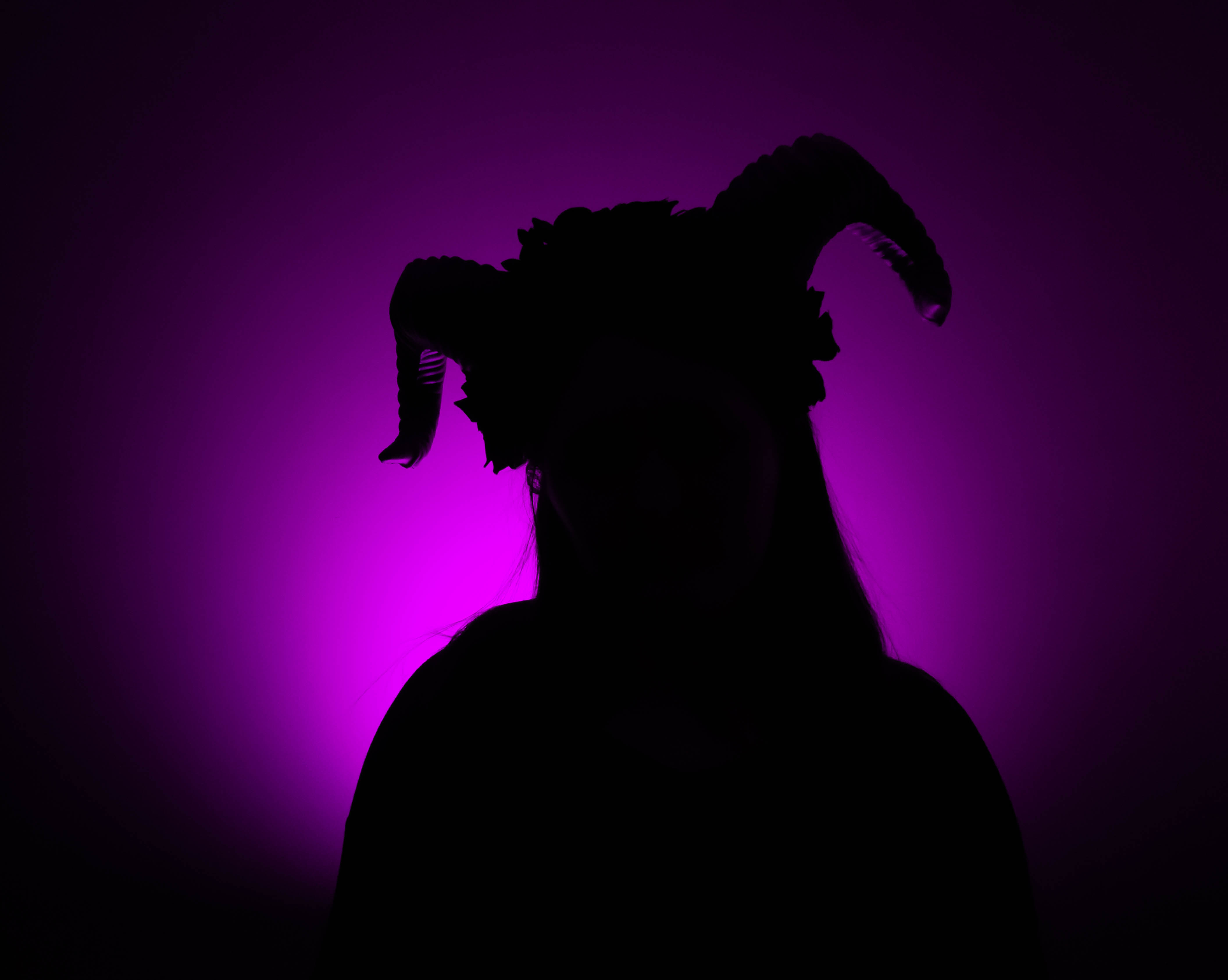 Shadow with horns against a purple light background.